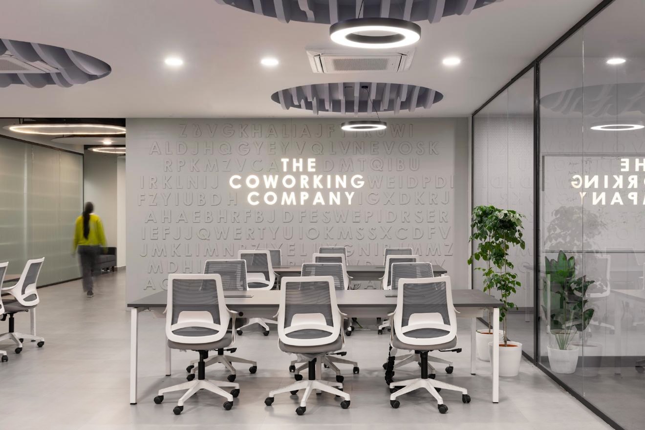 Team workspace in front of the lit Coworking Company letter wall